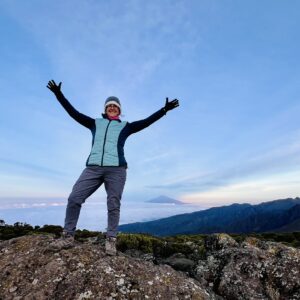 image of woman standing with arms raised above head on top of a mountain